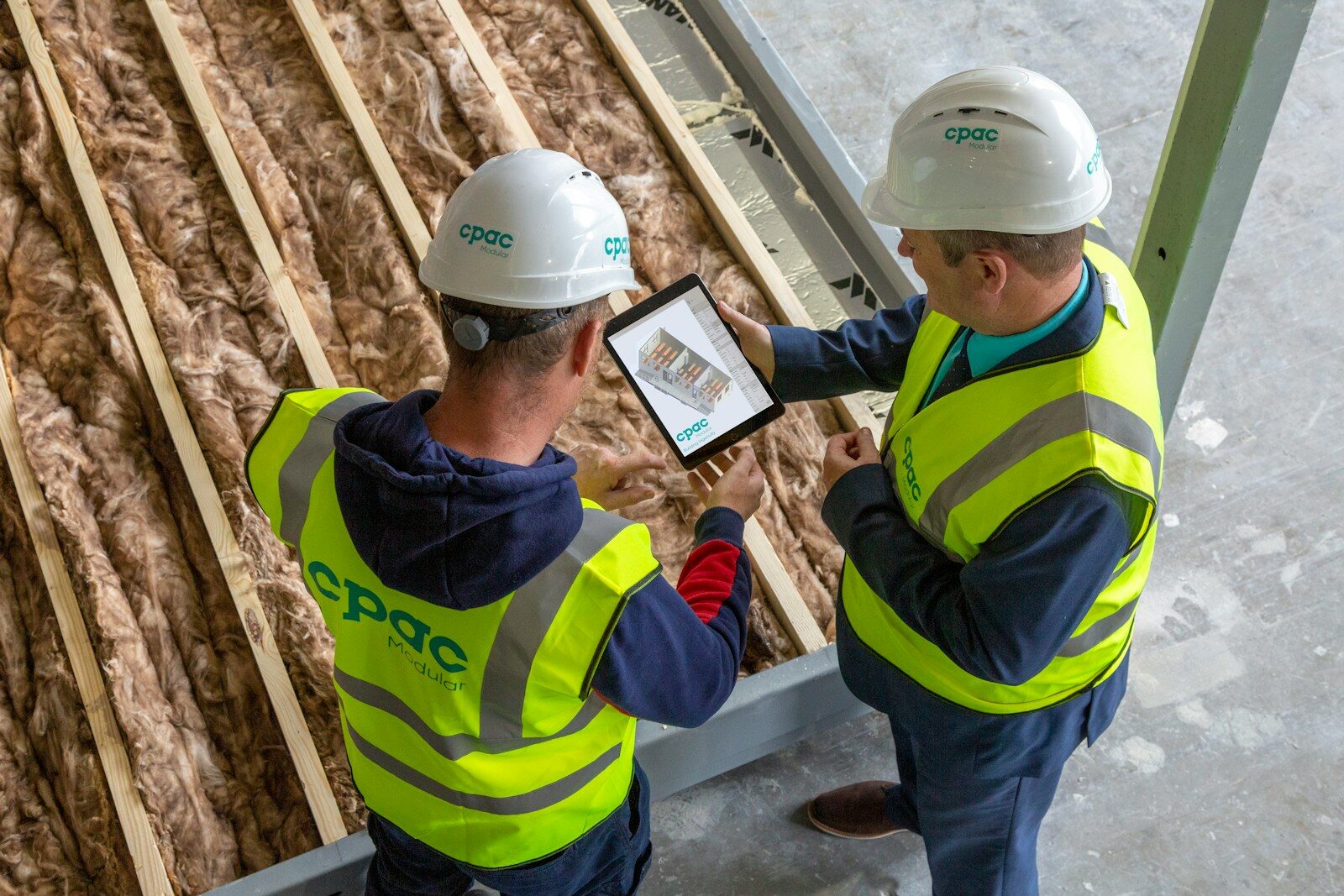 Two construction workers review plans on a tablet